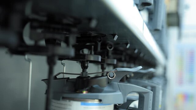 Close-up view of an industrial paint mixing machine. Mechanical arms and nozzles dispense and blend paint inside a container, showing the automated mixing process.