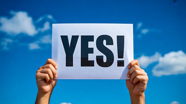Hands holding YES sign against bright blue sky symbolizing positivity motivation and approval

