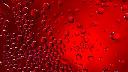 Macro water droplets of varying sizes on glass, formed by condensation. An abstract image with a red background, emphasizing texture and freshness.