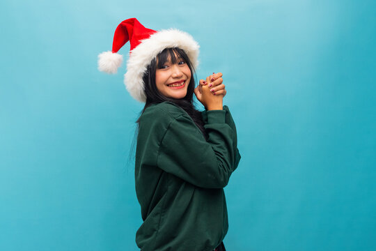Joyful woman in Santa hat claps hands cheerfully Ideal for Christmas celebration and fun festive visuals - Powered by Adobe
