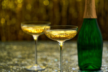 Champagne bottle and coupe glasses on a table, selective focus.