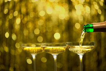 pouring champagne wine from bottle in a coupe glasses, selective focus. champagne poured in a champagne glases. © Igor Dudchak