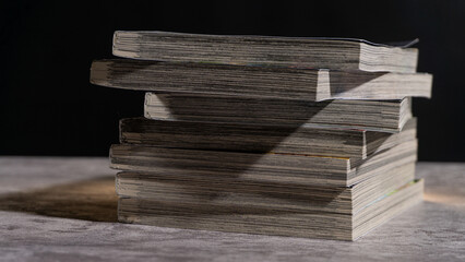 Uneven stack of worn paperbacks captured in side view, showing textured pages and natural aging, perfect for concepts of reading habits, study, or vintage media.
