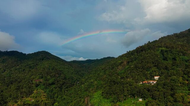 Spectacular Aerial Drone Shot of Double Rainbow Arching Over Lush Green Mountain Landscape After Rainfall