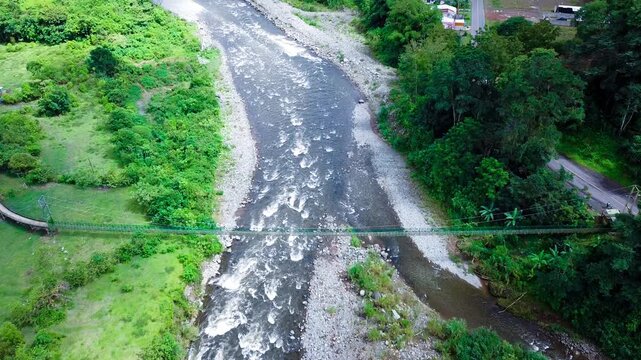 Aerial View of Suspension Bridge Over River in Lush Green Landscape