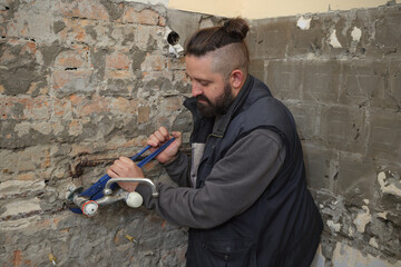 Home renovation, young plumber fixing or replacing old faucet in a bathroom, using adjustable wrench tool