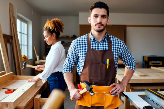 Portrait of Young Adult Caucasian Man Standing in Workshop with Female Colleague