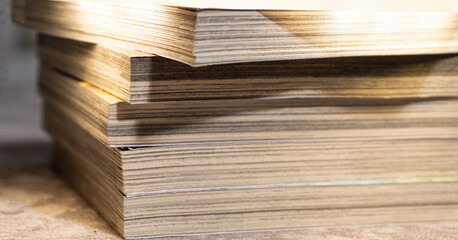 Low-angle shot of open and stacked books under bright light, featuring crisp paper texture and strong shadows, perfect for learning, reading, and knowledge themes.