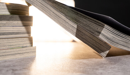 Close-up view of horizontal book stack with bright illumination from behind, showing worn paper edges and soft contrast, fitting for education or vintage reading visuals.