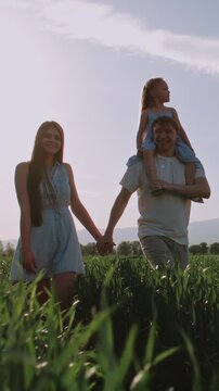 happy family father carrying daughter on shoulders parents holding hands golden hour parenting strong family bond connection