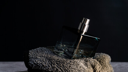 Glass perfume bottle tilted on soft fabric with angled lighting, showcasing reflections and premium design, fitting for fragrance promotions and elegant lifestyle visuals.