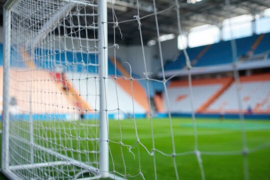 A classic football goal net, empty and pristine, against a blurred stadium background A front on view of an empty, white football goal net, perfectly taut and without any imperfections. The background - Powered by Adobe