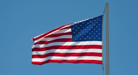 Fototapeta premium American flag waving proudly against a clear blue sky evokes patriotism and strength