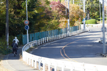 秋の朝の街のカーブの道路と自転車を乗るシニア男性の姿