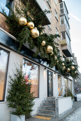 Christmas street decorations. Huge golden balls among the spruce branches at the top of the shop window.