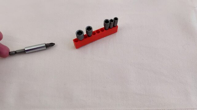Hex socket bit set neatly arranged on white fabric, red holder and screwdriver included, showcasing organized tools for repair, assembly, and precision work in a clean setup