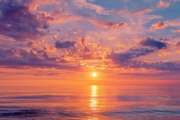 Obraz premium Vibrant sunrise over a calm ocean with colorful clouds reflecting on the water at dawn in a peaceful sky setting