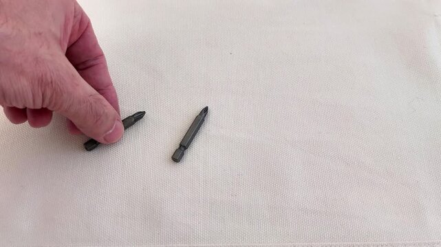 Screwdriver bits arranged on a white fabric base, showcasing organized detail and metallic texture in a simple, precise layout