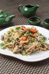 Spicy shredded chicken, arranged on a fan-shaped white porcelain plate, is placed on a placemat.
