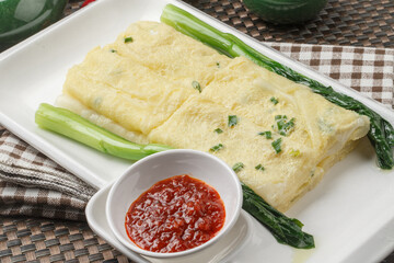 A rectangular white porcelain plate holds a Hong Kong-style egg pancake on a placemat.