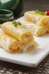 Shrimp rice noodle rolls were arranged on a rectangular white porcelain plate on a placemat.