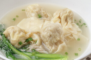 Wontons in a white porcelain bowl were placed on a placemat.