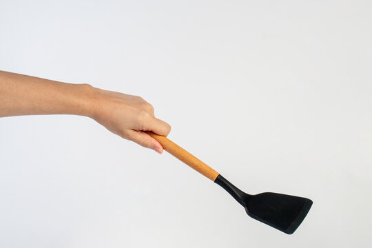 Hand with Black plastic kitchen spatula, kitchenware for cooking on white background.