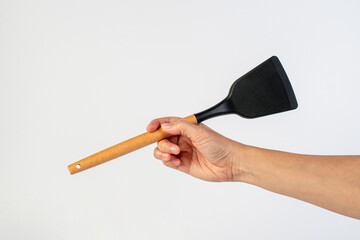 Hand with Black plastic kitchen spatula, kitchenware for cooking on white background.