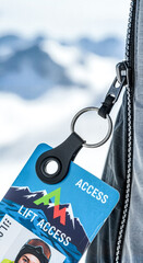 Ski lift access card hanging from zipper on jacket in snowy mountains  