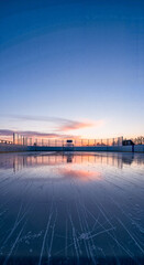 Sunset view over frozen ice rink reflecting colorful sky  