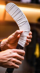 Hockey player gripping a stick with white tape in indoor arena  