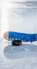 Ice hockey stick and puck on frozen rink surface with reflections  