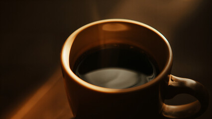 A cup of black coffee with light shining on it.
