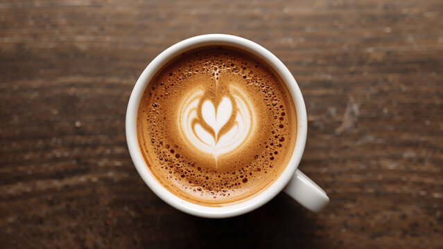 Overhead shot of a cup of coffee with latte art on a wooden surface.