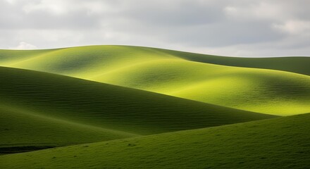 Obraz premium Rolling green hills under a cloudy sky, showcasing the beauty of nature's landscape.