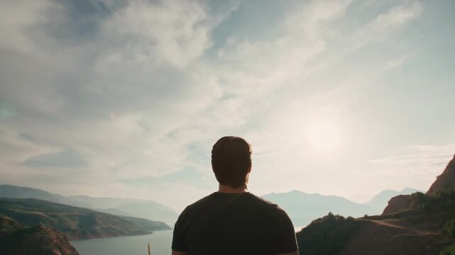Camera pulling back from sunrise revealing traveler standing still facing horizon mountain landscape unfolding concept of solitude inspiration harmony and peaceful outdoor awakening