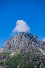 Majestic Mountain Peak with Cloud Crown Against Blue Sky