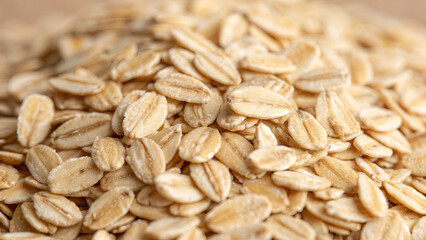A close-up view of a pile of raw oats on a wooden surface highlights their natural texture and color. Oats are a nutritious ingredient for various meals, promoting healthy eating habits