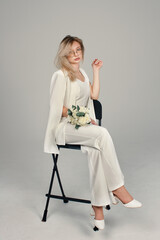 Portrait of a girl in a white suit holding flowers. Female portrait.	