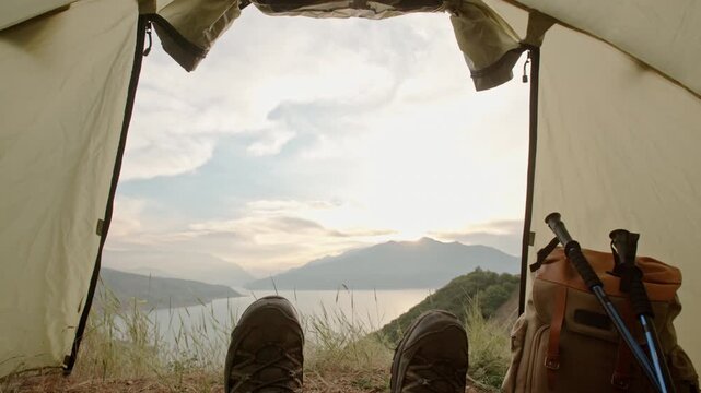 Morning sky above mountains camera moving slowly into tent revealing traveler resting inside concept of peace solitude relaxation freedom minimal lifestyle and mindful outdoor escape