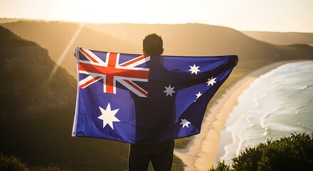 A person holding the australian flag on a hill overlooking the ocean at sunset with sun rays