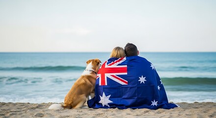 Couple wrapped in australian flag with dog on beach, symbolizing national pride and togetherness by the sea