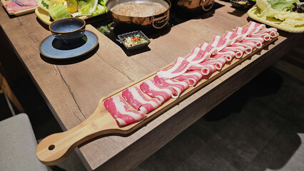 Premium sliced Snowflake beef and Premium pork sliced meat on a wooden board in a Japanese hotpot restaurant, vibrant textures and high-quality ingredients prepared for a comforting Asian shabu-shabu 