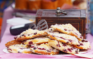 A tempting pile of freshly baked raspberry pastries dusted with sugar, displayed at a bustling riverside farmers market stall in Prague, Naplavka.
