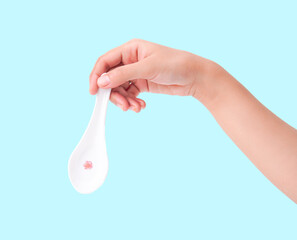 Hand holding elegant white ceramic spoon with delicate design on blue.