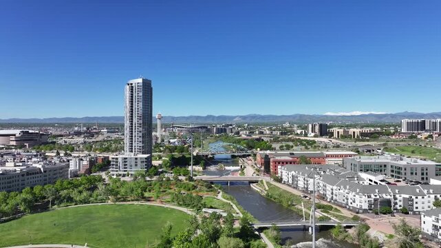 Aerial view of Denver with the Broncos stadium in the distance as the drone flies sideways under a clear blue sky.