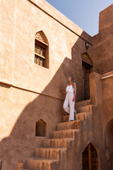 Woman exploring traditional omani architecture enjoying sunlight