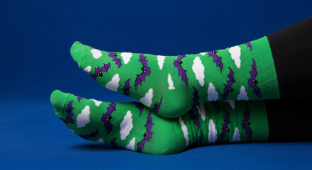 A pair of green socks with bats and white spots on a blue background
