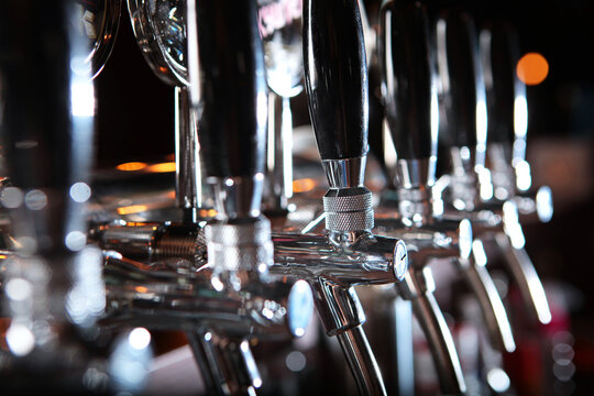 Beer taps in the pub. A special accent. The concept of alcohol. Vintage style. Craft beer. The bar table. Shiny steel cranes. Nobody. Selective focus.