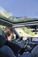 A focused driver sits behind the wheel in a modern car, navigating busy city streets. A large GPS display guides the route, highlighting the tech-enabled, urban driving experience.